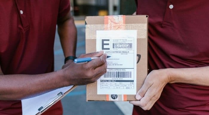 Delivery People Holding a Package with a USPS Priority Mail Express shipping label.